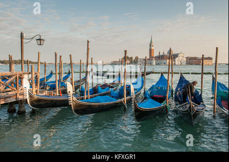 Gondole ormeggiate presso Riva degli Schiavoni a San Marco, Venezia, Italia. La laguna veneta e l'isola di San Giorgio maggiore sullo sfondo. Foto Stock