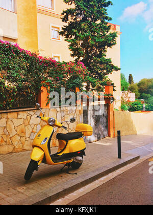 Retrò giallo scooter parcheggiate su strette strade di Barcellona, Spagna. immagine ha un forte effetto vintage applicato. Foto Stock