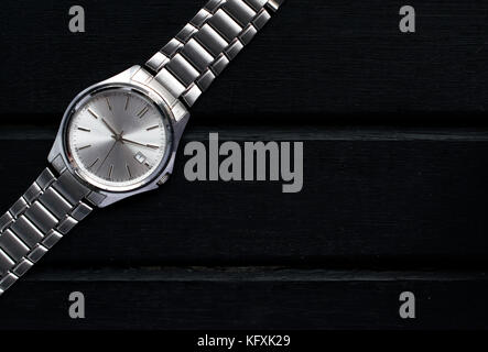 Acciaio inox silver mens orologi da polso su un nero superficie di legno e con un sacco di spazio copia e il contrasto Foto Stock