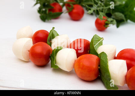 Caprese di mozzarella, pomodoro cherry e basilico, tradizione mediterranea, snack su bianco Foto Stock