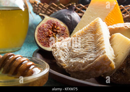 Composizione alimentare con un pezzo di formaggio ammuffito, miele, figg. Foto Stock