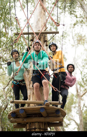 Gli amici di ottenere pronto per la zip line a park in una giornata di sole Foto Stock