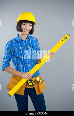 Ritratto di donna architetto azienda attrezzature di misurazione contro uno sfondo grigio Foto Stock