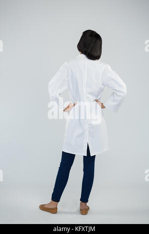 Vista posteriore del medico in piedi con le mani sui hip contro uno sfondo bianco Foto Stock