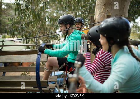 Gli amici di ottenere pronto per la zip line a park in una giornata di sole Foto Stock