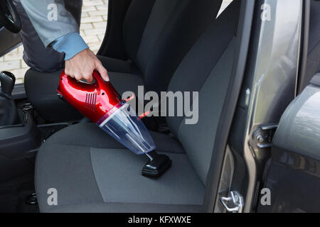Voce maschile auto service personale auto pulizia con aspirapolvere portatile Foto Stock