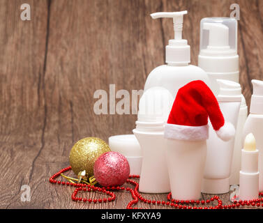 Natale skincare cosmetici. Vari prodotti cosmetici per la cura del viso e del corpo con Santa hat su una superficie di legno. Copia dello spazio. Vendita di Natale o il regalo di co Foto Stock