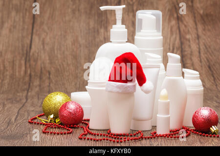 Natale skincare cosmetici. Vari prodotti cosmetici per la cura del viso e del corpo con Santa hat su una superficie di legno. Copia dello spazio. Vendita di Natale o il regalo di co Foto Stock