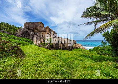 Escursioni di un sentiero nel deserto a mighty rosse rocce di granito nel lussureggiante verde erba ad anse songe, la digue, Seicelle Foto Stock