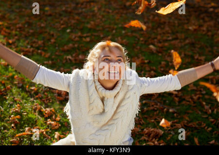 Donna che gioca con le foglie in esterno Foto Stock