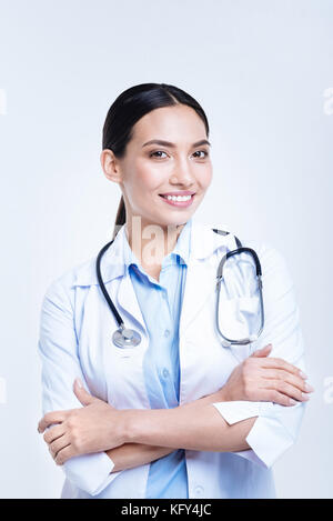 Allegro medico donna la piegatura delle sue braccia e sorridente Foto Stock