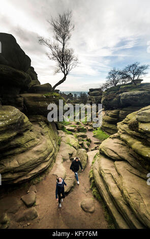 La gente esplora le rocce di Brimham, una collezione di formazioni rocciose equilibranti su Brimham Moor nella zona di Nidderdale di straordinaria bellezza naturale. Foto Stock