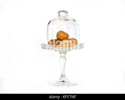 Piccoli biscotti di mandorle in un vaso di vetro su una gamba alta sotto la calotta in vetro isolato Foto Stock