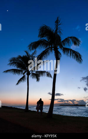 Silhouette di una giovane guardando una bella tropicale Hawaiiano tramonto sull'oceano pacifico nella magica isola di Oahu, HI. Foto Stock
