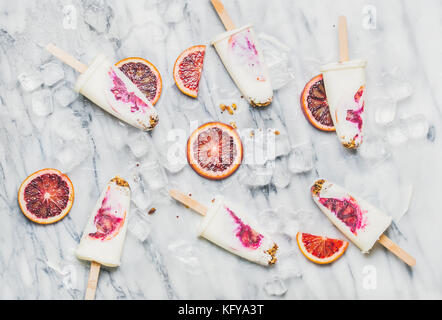 Arancio sanguigno, yogurt e granola popsicles su cubetti di ghiaccio Foto Stock