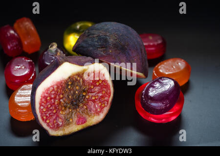 Dolce, fichi maturi su uno sfondo colorato e caramelle. Foto Stock