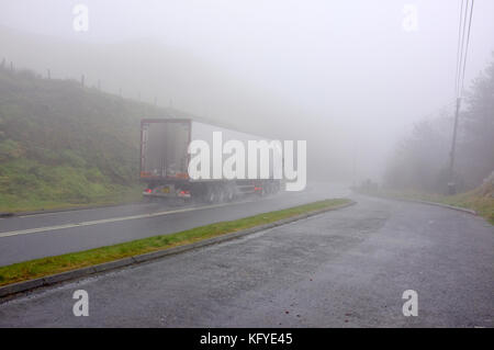 Un autoarticolato aziona attraverso nebbiose meteo in Galles Centrale. Foto Stock