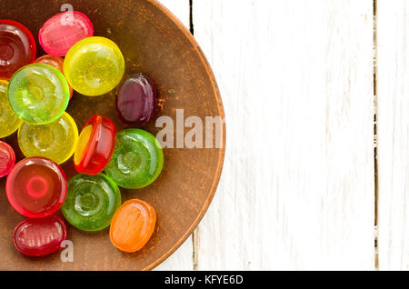 Luminoso multicolore di candy su un piattino di colore marrone. Tavolo bianco. Foto Stock