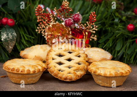 Selezione di golden brown pasticci di carne macinata con festa di Natale decorazioni in background Foto Stock