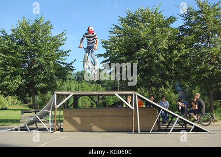 Gli adolescenti di eseguire trucchi di bicicletta in un parco Foto Stock