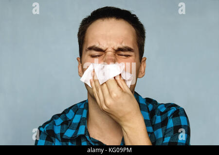L'uomo ha un naso che cola. la persona con un freddo starnutisce in un fazzoletto. snot proveniente dal naso. Foto Stock