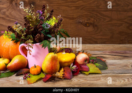 Tabella di ringraziamento centrotavola con fiori ed erba in rosa vaso Anfora, zucche, mele, pere sul legno rustico sfondo, copia spa Foto Stock