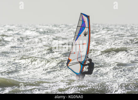 Windsurf in mare in una giornata di vento con Sun che riflette nell'acqua. Foto Stock