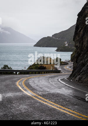 Strada tortuosa lungo il lago Wakatipu che conduce a Queenstown in Nuova Zelanda isola del sud in un giorno di pioggia Foto Stock