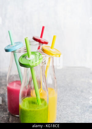 Varie del frullato colorato in bottiglie con acqua potabile cannucce: verde,giallo,rosso, vista frontale, close up Foto Stock