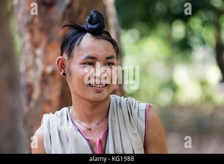 Close up ritratto di giovane uomo di bamar con capelli lunghi legati in un nodo in kayin villaggio vicino alla città di Hpa-an, kayin membro / karen stato, myanmar / burm Foto Stock