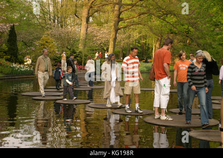 I turisti a piedi su legno pietre miliari. In primavera i giardini Keukenhof Lisse, Paesi Bassi. Noto anche come il giardino d'Europa, è uno dei più grandi del mondo giardini di fiori. Foto Stock