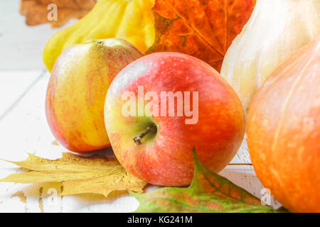 Zucca e Patty pan, mele e acero, rovere foglie gialle su una bianca tavolo in legno. raccolto autunnale. Foto Stock