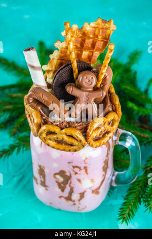 Freakshake dal frullato di rosa, crema. monstershake con un cioccolato, canna, salatini, cialde e marshmallow. extreme frullato in una giara di mason. verde Foto Stock