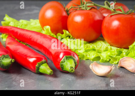 Peperoncino rosso, pomodori, Sadat e aglio su un marmo grigio sfondo Foto Stock