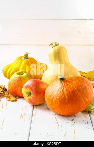 Zucca e Patty pan, mele e acero, rovere foglie gialle su una bianca tavolo in legno. raccolto autunnale. Foto Stock