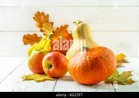 Zucca e Patty pan, mele e acero, rovere foglie gialle su una bianca tavolo in legno. raccolto autunnale. Foto Stock