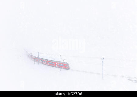 Bernina Express al Passo Bernina durante una tempesta di neve, in Engadina, nel canton Grigioni, Svizzera, Europa Foto Stock