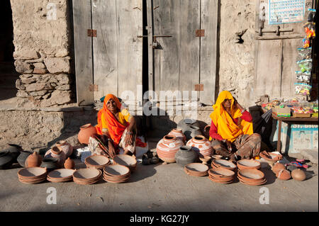 Due donne in saris giallo e arancio, che vendono pentole e ciotole di terracotta decorate a mano, villaggio di Diggi, Rajasthan, India, Asia Foto Stock