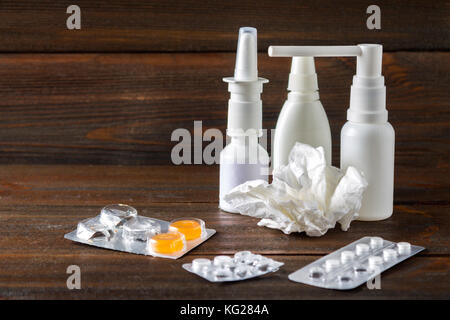 Spray nasale, gocce nasali, pillole nel blister, candy dalla tosse sul tavolo. moderni farmaci per il raffreddore, influenza. trattamento della malattia. Foto Stock