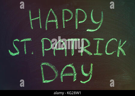 La scritta verde con gesso su una lavagna: happy st. Patrick's day. Foto Stock