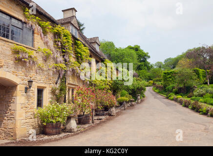 Tradizionali case di pietra da un percorso di villaggio e giardini, nelle zone rurali a Cotswolds, su una soleggiata giornata estiva . Foto Stock