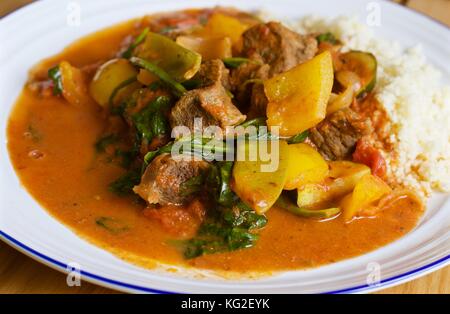 Curry di manzo saag gosht fatto in casa con riso bianco su un piatto bianco su tavola di quercia Foto Stock