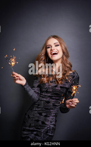 Donna sorridente con sparkler ridere in studio shot Foto Stock