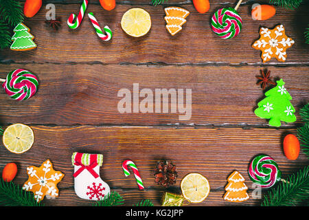 Il natale di panpepato biscotti fatti in casa su un tavolo di legno con canditi, albero di natale rami e Nuovo Anno decorazioni. xmas sfondo del telaio Foto Stock