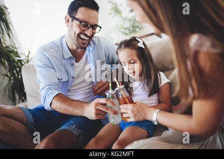 La famiglia felice di bere succo di frutta insieme nella loro casa Foto Stock