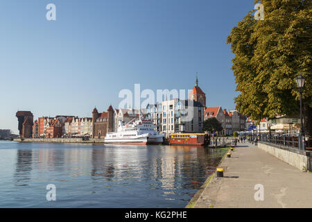 Vista di due barche e vecchi edifici lungo il ponte lungo waterfront presso le principali città e il lungomare in Gdansk, Polonia, in una giornata di sole. Foto Stock