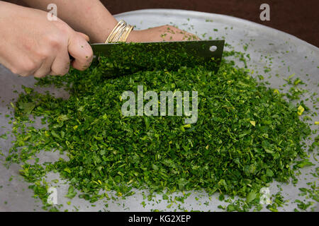 Donna tritare verdure con il coltello per sminuzzare in vassoio grande Foto Stock