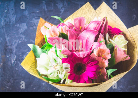 Bouquet di fiori da Lily, gerbera, rose bianche e alstroemeria contro lo sfondo di un oscuro parete in calcestruzzo. Una vacanza, un dono. Foto Stock
