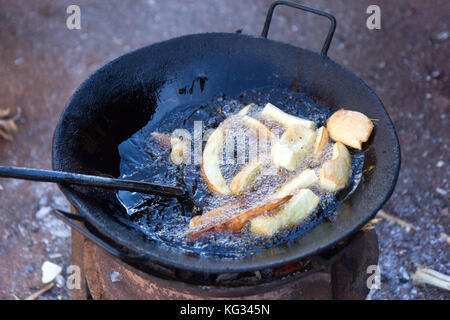 La Manioca di frittura in olio in un tegame sul fuoco stufa. Foto scattata in Najja, Uganda il 9 maggio 2017. Foto Stock
