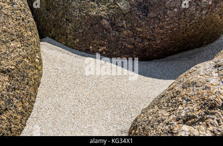 Round pietre di granito nella sabbia sulla spiaggia. Foto Stock